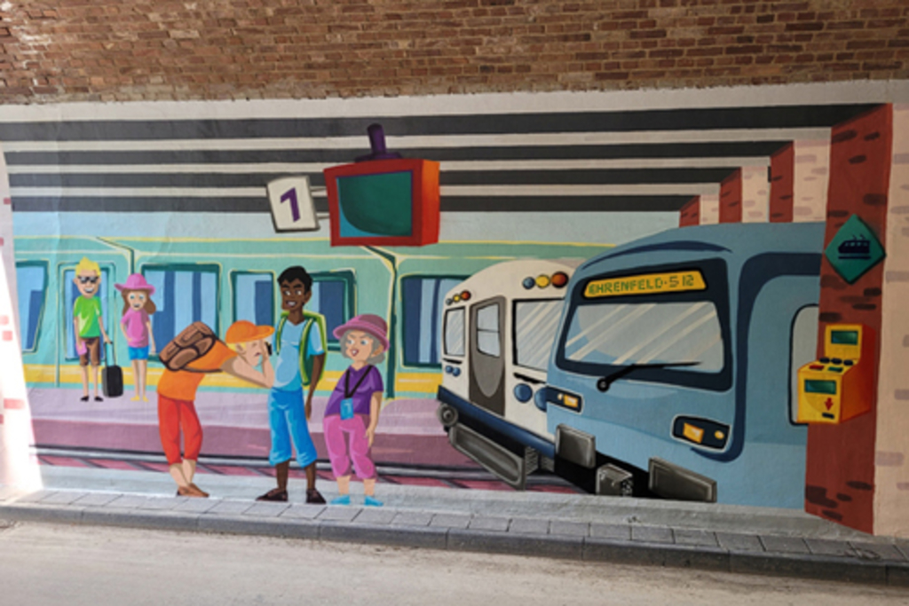 Illusionsmalerei in Unterführung Pingenweg Motiv „Bahnhof Lindweiler“: wartende Menschen fotografierend