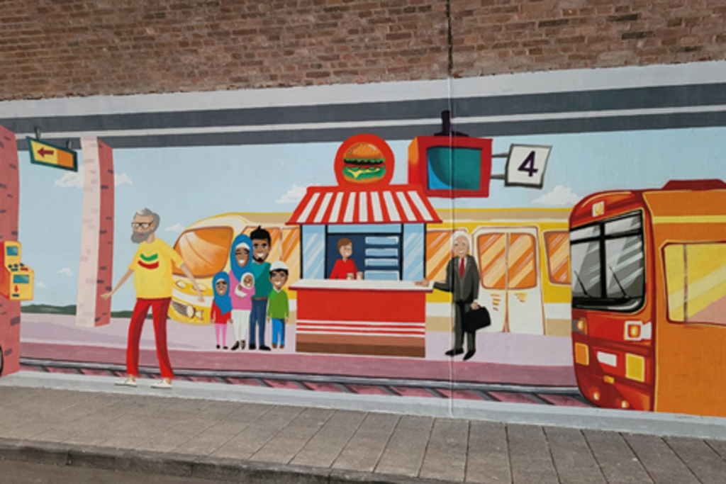 Illusionsmalerei in Unterführung Pingenweg Motiv „Bahnhof Lindweiler“: wartende Menschen an Hot Dog Stand