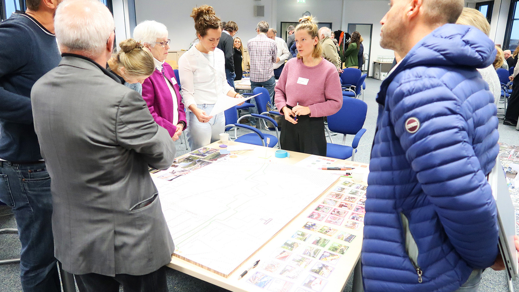 Workshop-Teilnehmende stehen um eine Arbeitsstation herum und beteiligen sich