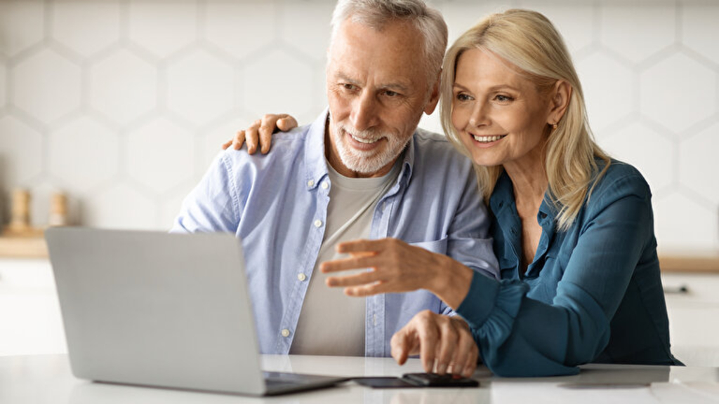 Eine älteres Paar sitzt in ihrer Küche vor einem Laptop, Link auf Die Pflichtversicherung - Stadt Köln