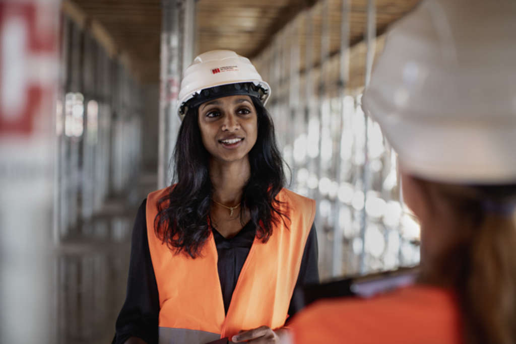 Eine Ingenieurin unterhält sich auf einer Baustelle mit einer anderen Ingenieurin, Link auf Wir suchen Sie!
