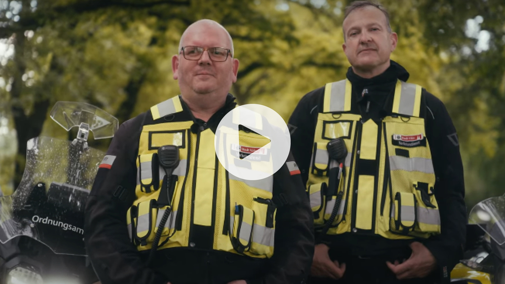 Zwei Verkehrsdienstmitarbeitende in Uniform, Link auf Mach Köln achtsamer - Bewirb dich jetzt beim Verkehrsdienst der Stadt Köln - YouTube