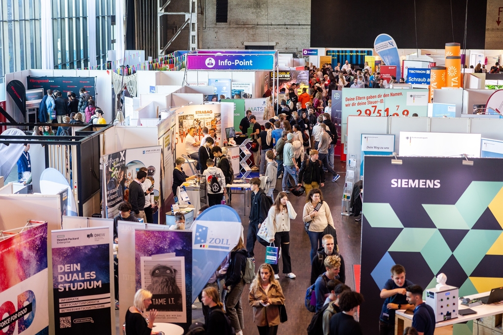 Verschiedene Messe Stände einer Job-Messe mit Besucher*innen