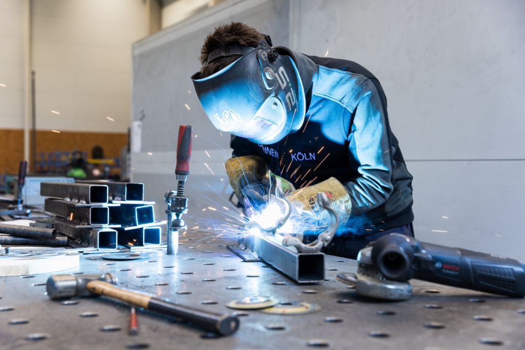Eine Person schweißt Metall, dabei fliegen Funken.