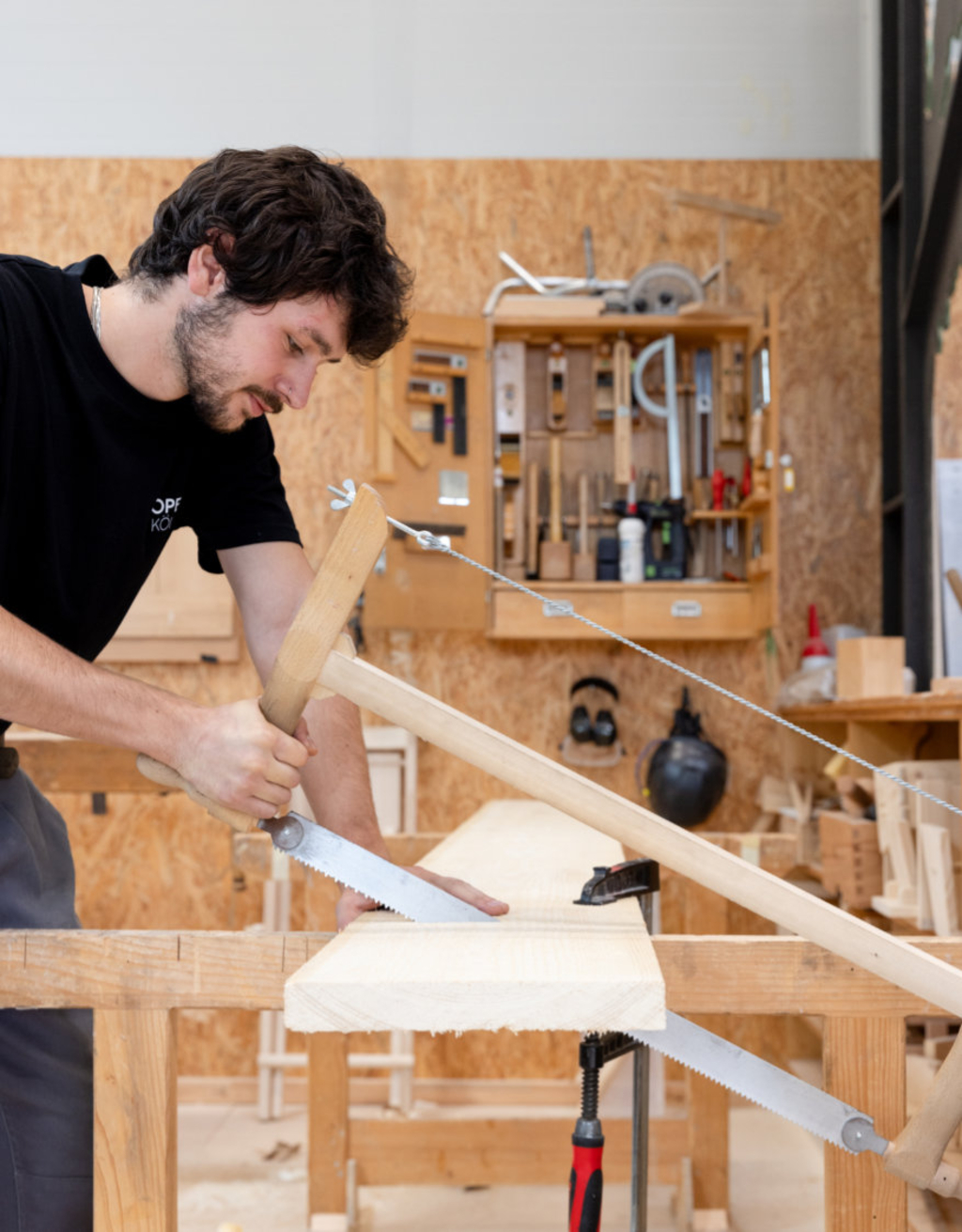 Ein Mann sägt mit einer Säge ein Holzbrett.