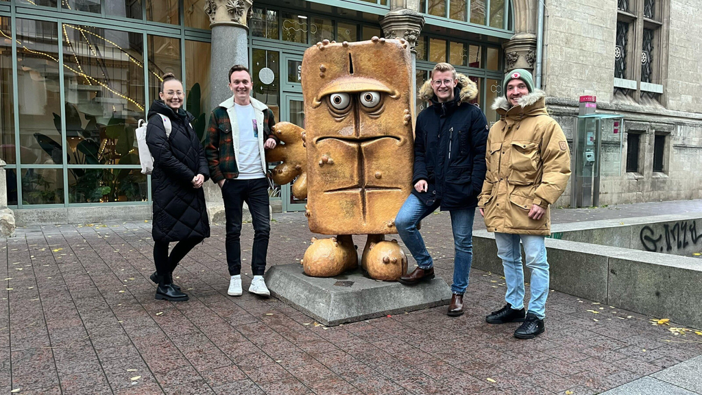 Vier Studierende neben einer Bernd das Brot-Statue