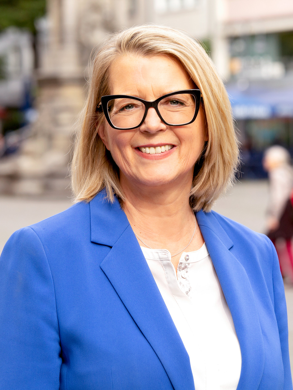 Stadtdirektorin Andrea Blome lächelt in die Kamera, im Hintergrund unscharf der Kölner Alter Markt