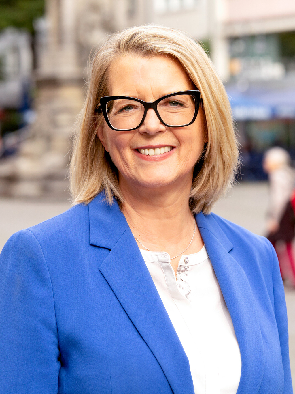 Stadtdirektorin Andrea Blome lächelt in die Kamera, im Hintergrund unscharf der Kölner Alter Markt