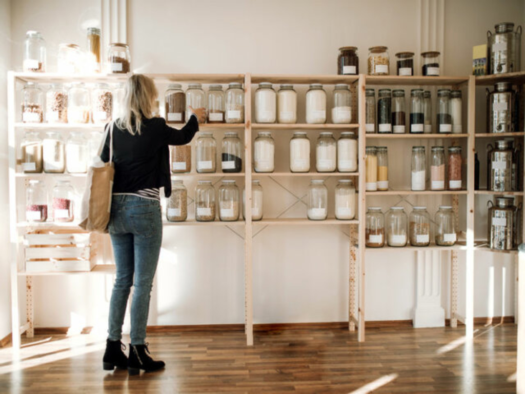 A young happy woman buying groceries in zero waste shop. Copy space.