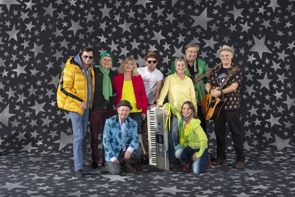 Gruppe von Musiker*innen mit Instrumenten vor Sternenhintergrund