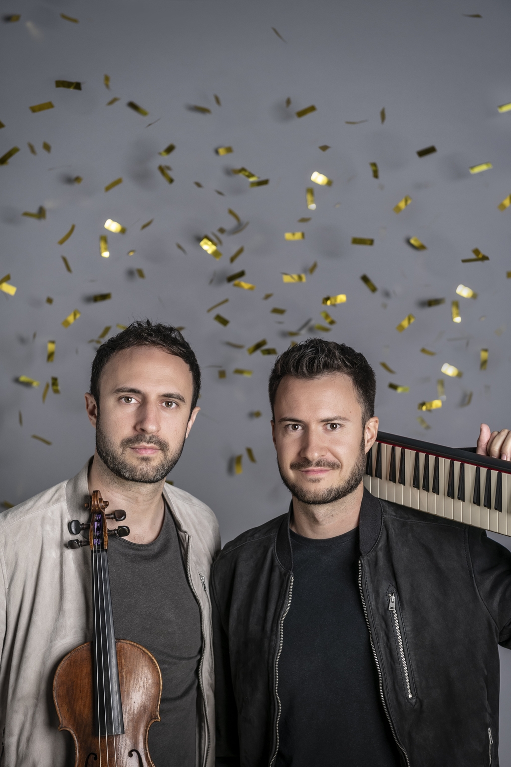 Foto mit Ass-Dur; die zwei Musiker halten eine Geige und ein Keyboard in der Hand; im Hintergrund Konfetti