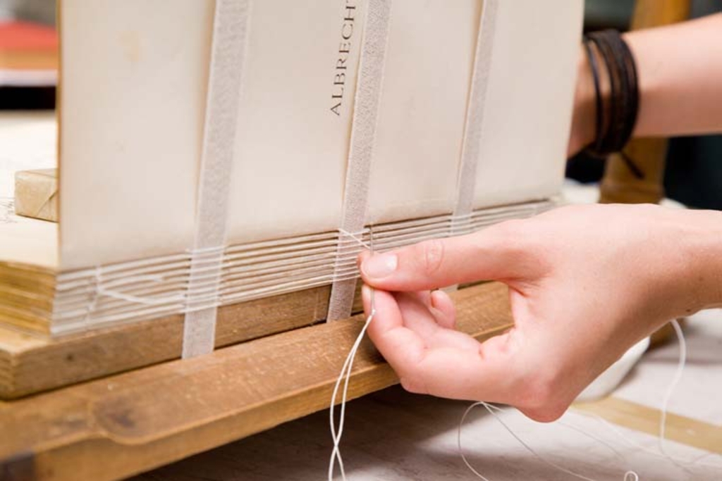 Eine Hand dieeine Fadenheftung ausführt