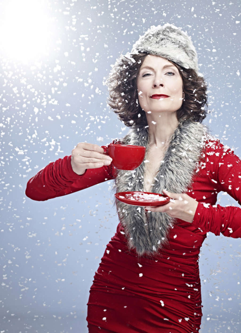Madeleine Sauveur als elegante Weihnachtsfrau gekleidet. Hält eine rote Tasse zum Trinken bereit.