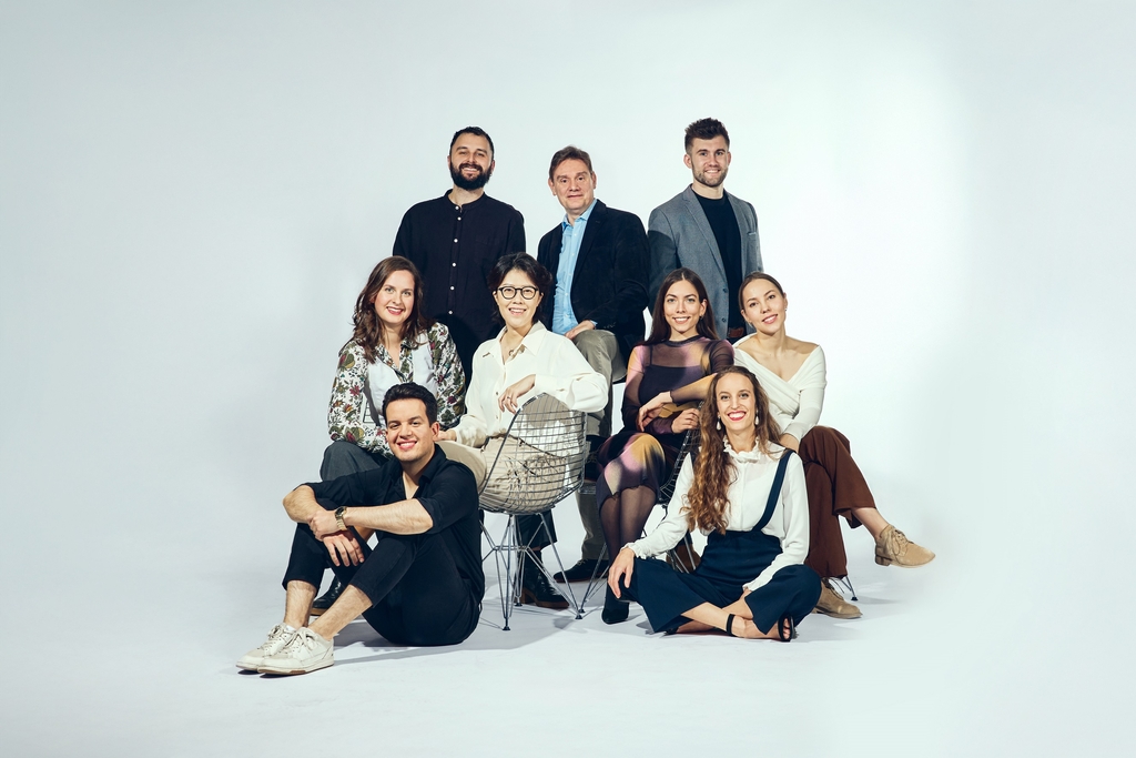 Gruppenporträt des Internationalen Opernstudios der Oper Köln, sitzend und stehend, neun Personen