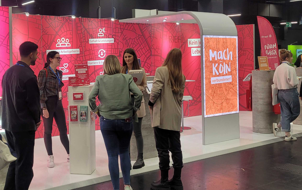 Foto vom Mach-Köln Messestand mit Mitarbeitenden