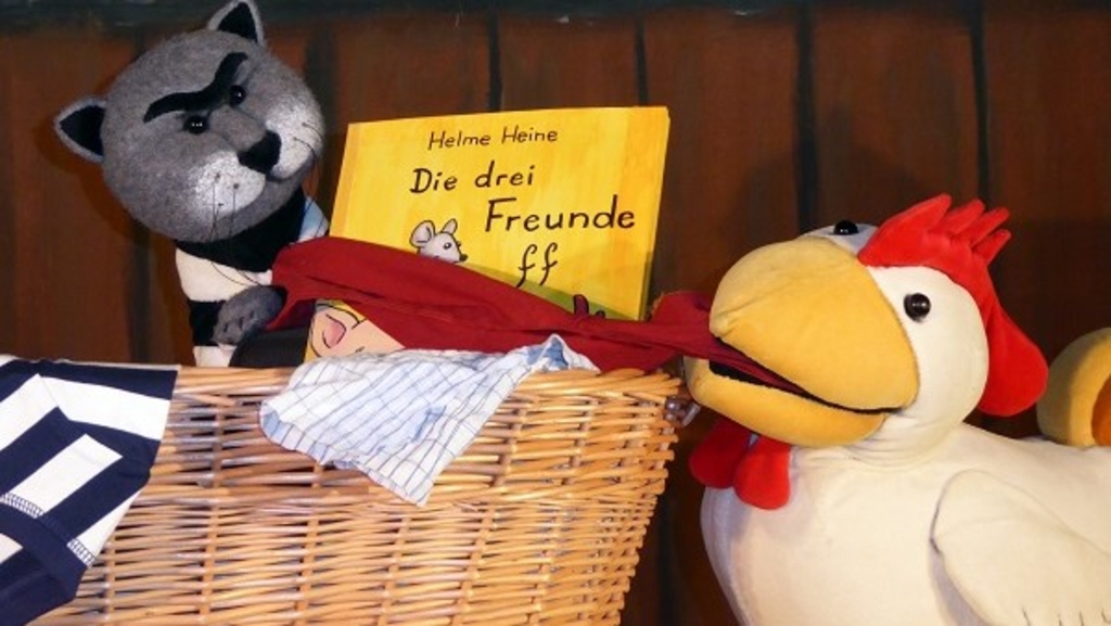 Foto von zwei Handpuppen, eine Katze und ein Hahn, die sich um ein Tuch streiten