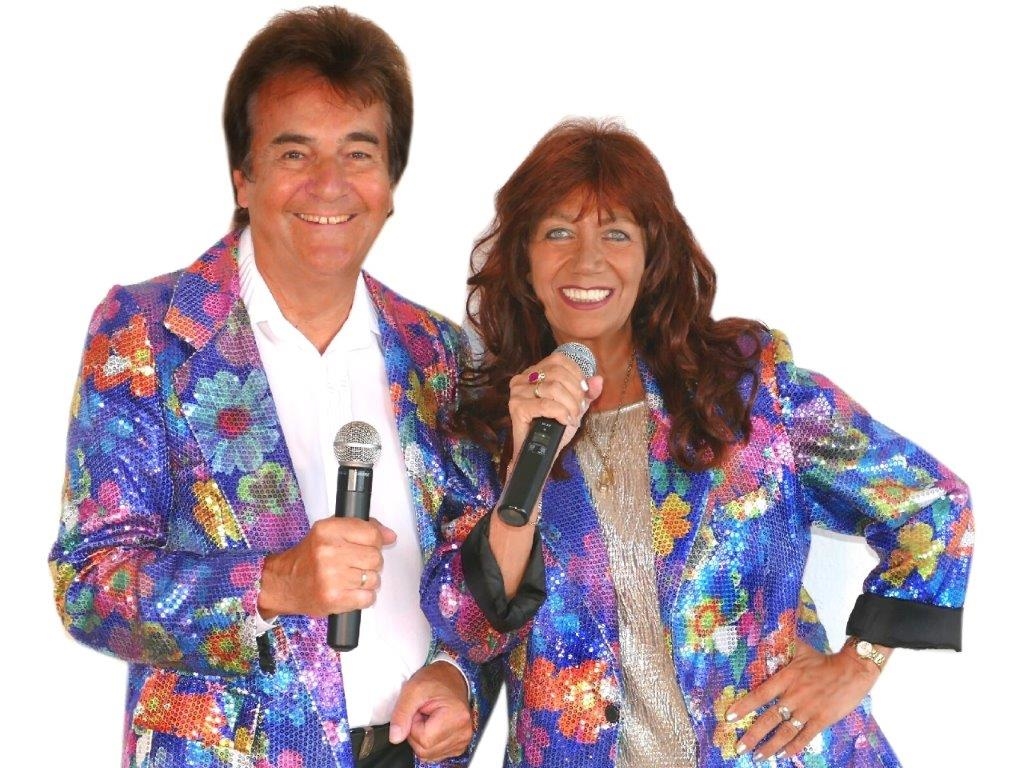 Marina Kirsten und Ian Bishop mit Mikrophonen und im Bühnen-Outfit