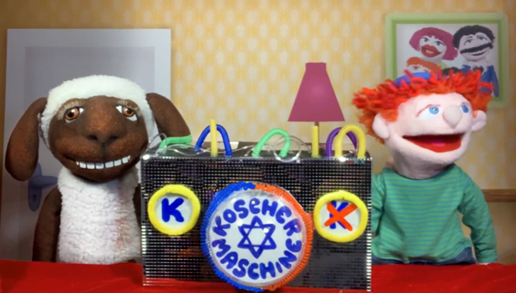 Bild aus dem Puppentheater mit zwei Handpuppen und der Koscher-Maschine