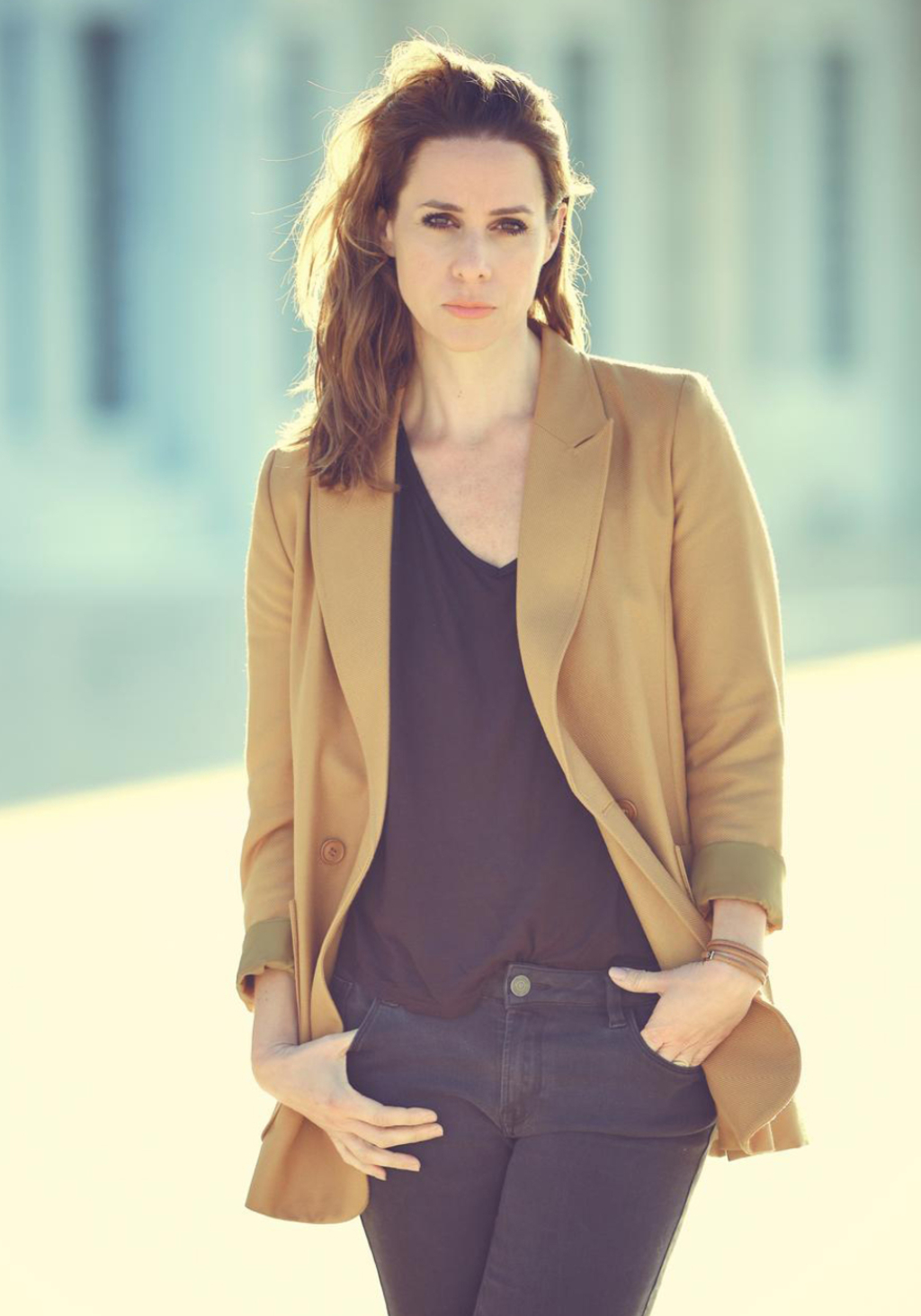 Foto von der Autorin Natalie Amiri. Sie trägt einen gelben Blazer und schaut ernst in die Kamera