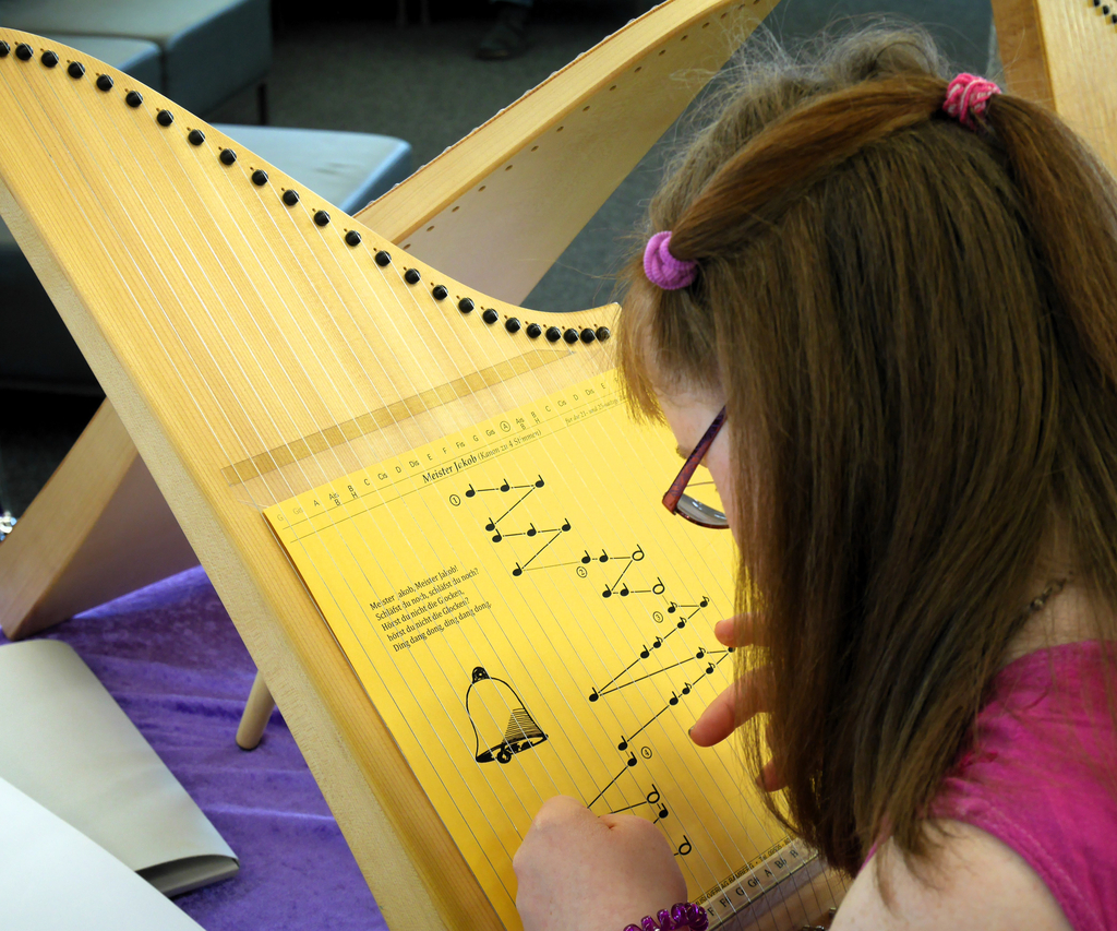 Kind an einer Tischharfe
