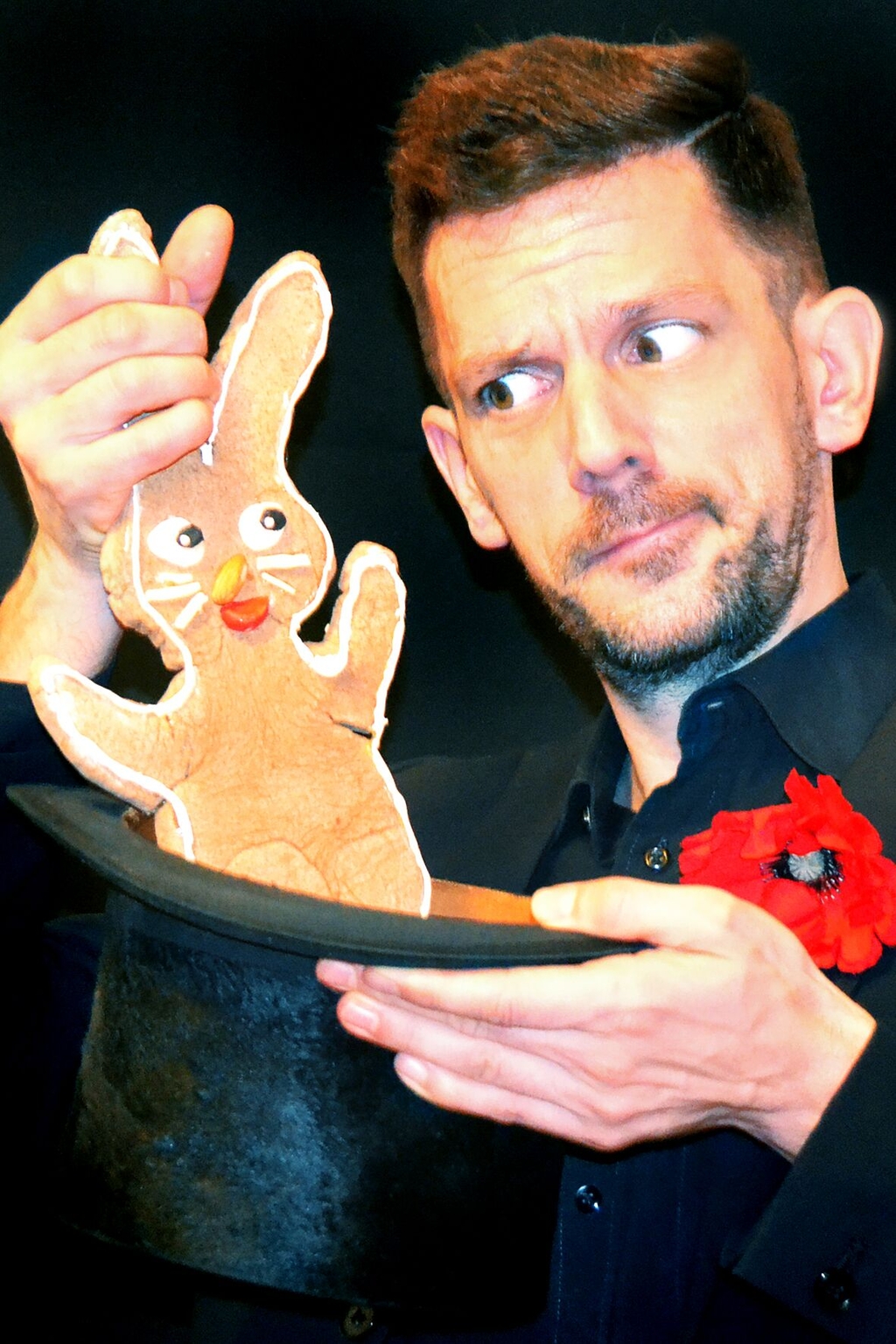 Der Zauberkünstler Urs Jandel ist abgebildet wie er einen Keks in Form eines Hasens aus einem Zylinderhut zieht.
