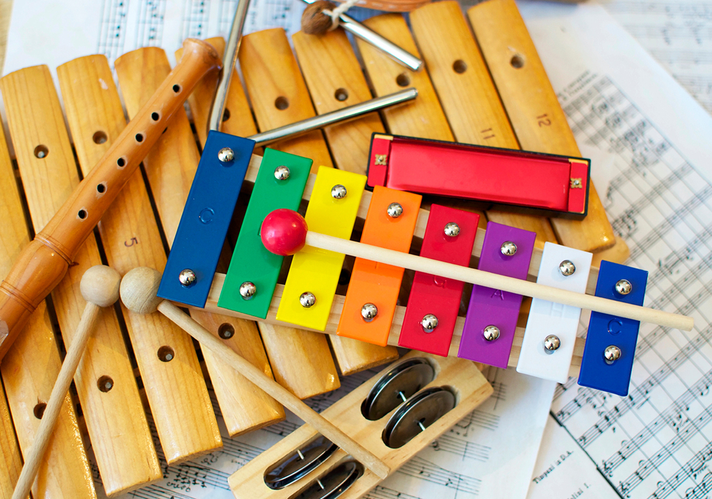 verschiedene bunte Instrumente und ein Xylopho aus Holz liegen auf Notenblättern