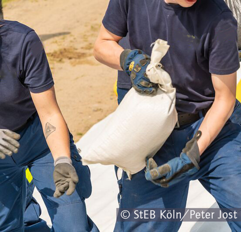 Personen, die einen gefüllten Sandsack weiterreichen