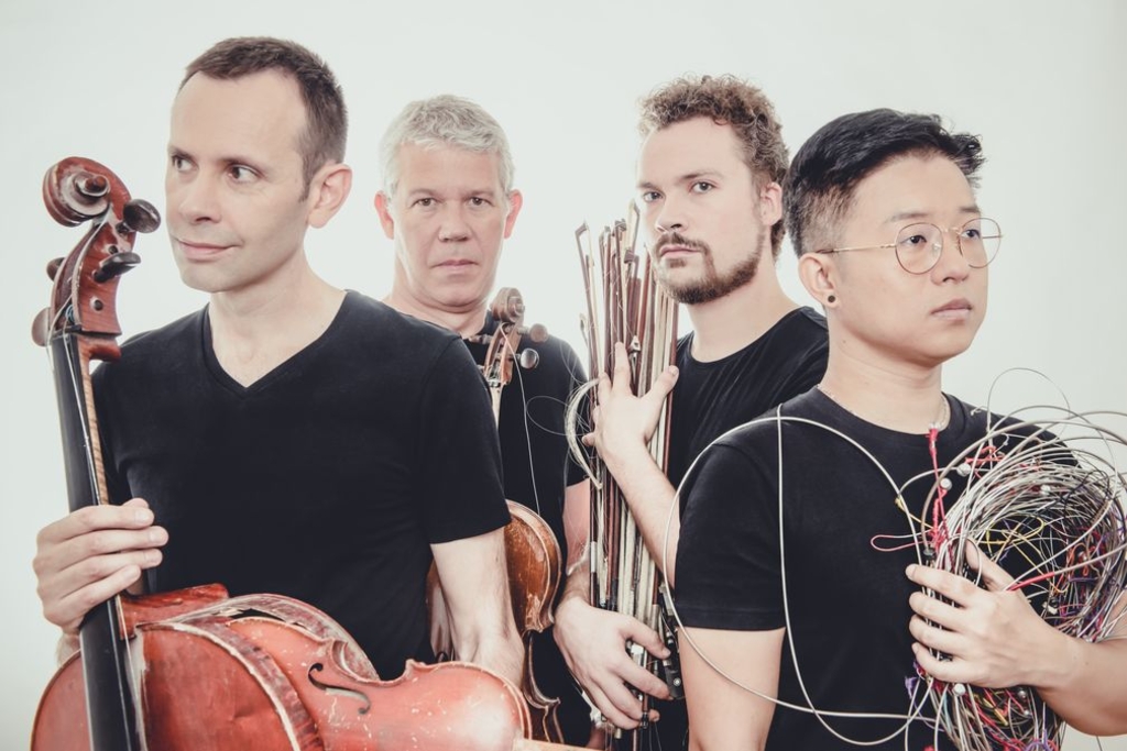 Das Streichquartett Quatuor Diotima ist abgebildet. Die vier Musiker tragen ihre Instrumente, sowie Streichbögen und verschiedene Kabel in den Händen.