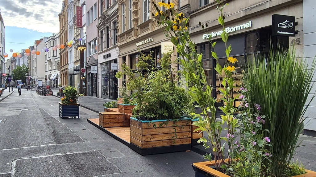 Foto von Sitzmobiliar auf der Ehrenstraße. Zu sehen sind begrünte "Sommermöbel", die zum Flanieren und Pausieren einladen., Link auf Neugestaltung der Ehrenstraße