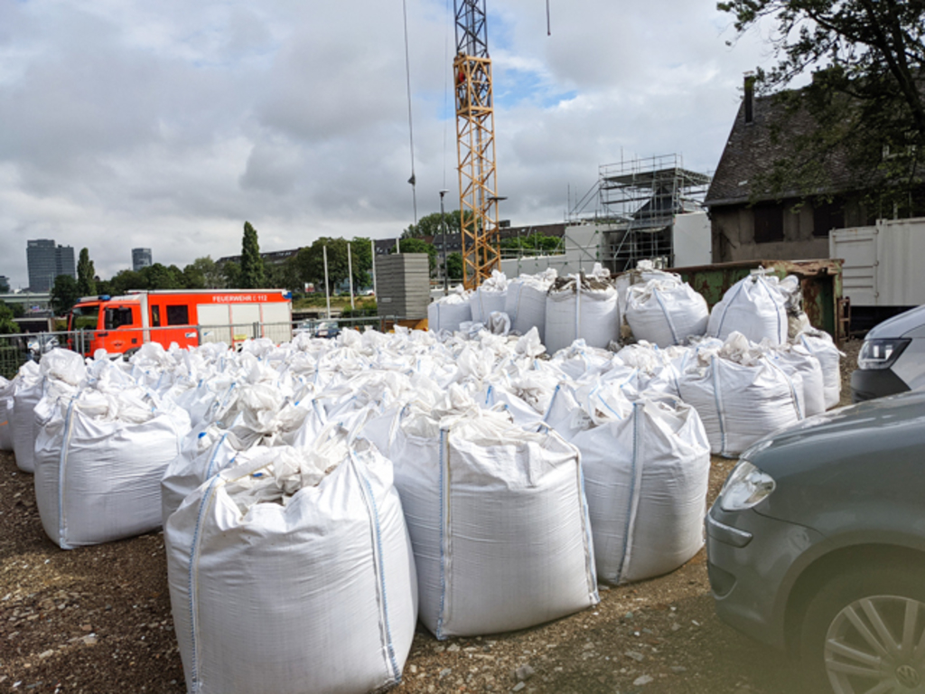 mehrere Säcke mit Strahlmitteln an der Baustelle, im Hintergrund steht ein Feuerwehrauto