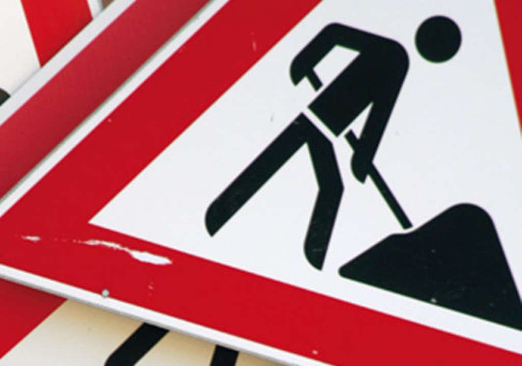 Verkehrsschild 123 - Das Schild ist ein rotes Dreieck mit einem Männchen in der Mitte, das auf einer Baustelle arbeitet. 