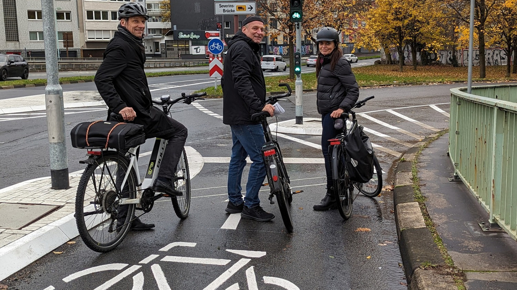 Beigeordneter Ascan Egerer, Fahrradbeauftragter Jürgen Möllers und Susanne Rosenstein vom Amt für Verkehrsmanagement stehen mit ihren Fahrradrädern an der neuen Ampelanlage an der Tel-Aviv-Straße auf Höhe der Severinsbrücke (von links).