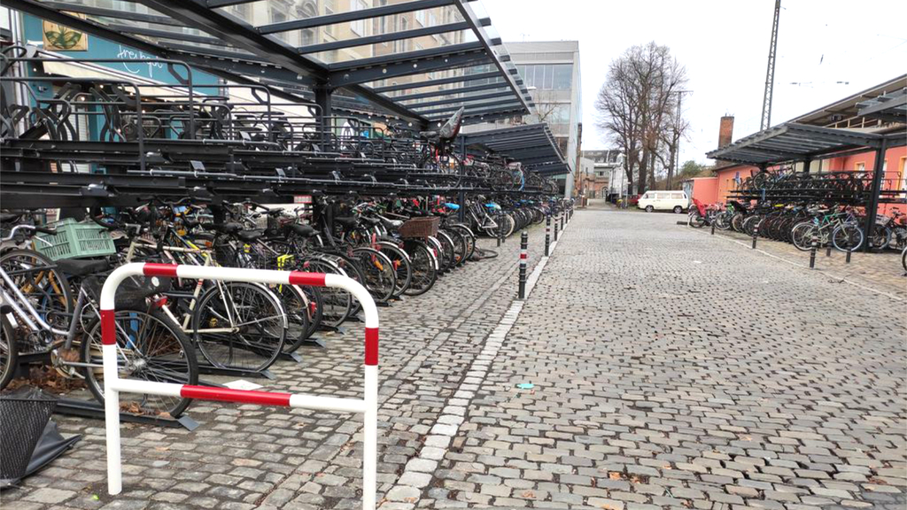 Foto eines überdachten Doppelstockparkers für Fahrräder am Bahnhof Köln Süd. Fast alle Plätze sind mit Fahrrädern belegt.