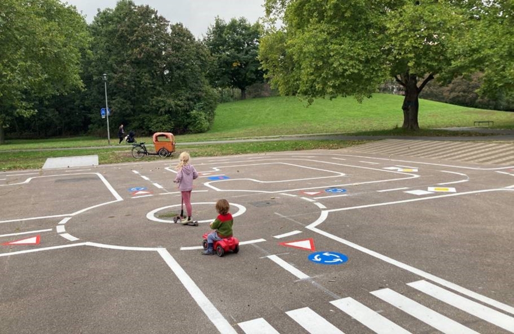 Zwei Kinder mit Tretroller und Rutschauto auf dem neuen Verkehrsübungsplatz im Vorgebirgspark