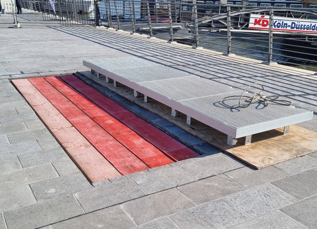 Zu sehen ist ein Zugang zum Rhein mit geöffneter Gitterrostabdeckung. Über diesen haben Rettungskräfte Zugang zum Rhein unterhalb der Kragplatte.