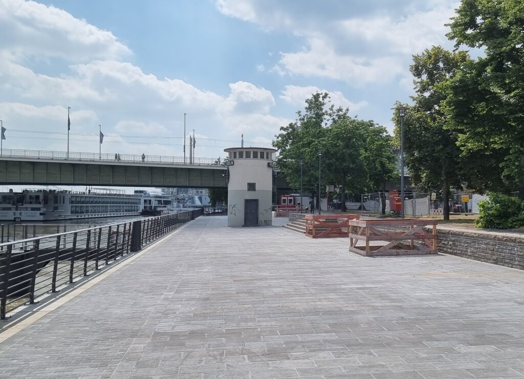 Zu sehen ist die fertig gepflasterte Rheinpromenade, Kragplatte mit Blick auf den Rheinpegel und die Deutzer Brücke