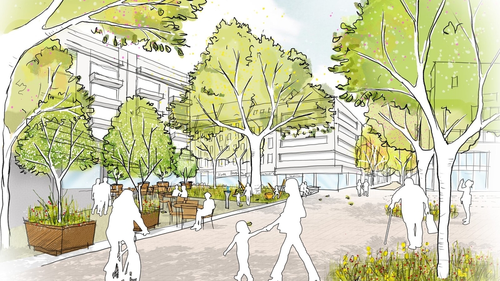 Visualisierung der geplanten Umgestaltung der Platzfläche auf dem Willy-Millowitsch-Platz. Zu sehen sind viele Fußgänger*innen, die flanieren oder auf Sitzgelegenheiten Pause machen. Zudem ist ein Radfahrer zu sehen. Der Platz ist sehr grün, ein Wasserbrunnen ist zu sehen.