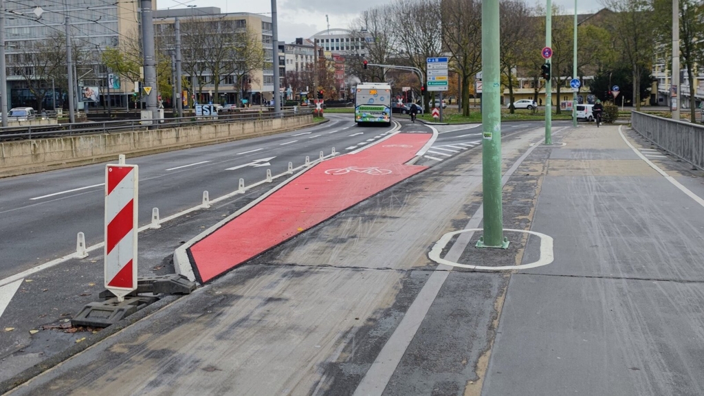 Zu sehen ist die neue Überführung von der Deutzer Brücke in Richtung Mindener Straße / Deutzer Freiheit. Im Hintergrund fährt eine Radfahrerin über den neuen Radfahstreifen, der rot eingefärbt ist.