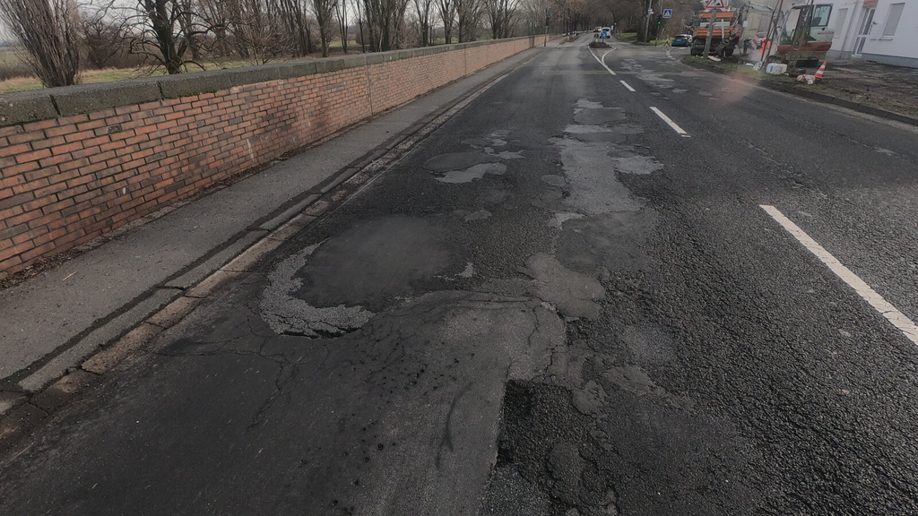 Blick auf die Neusser Landstraße in Höhe der Hausnummer 100. Der Asphalt der Fahrbahn ist sanierungsbedürftig.