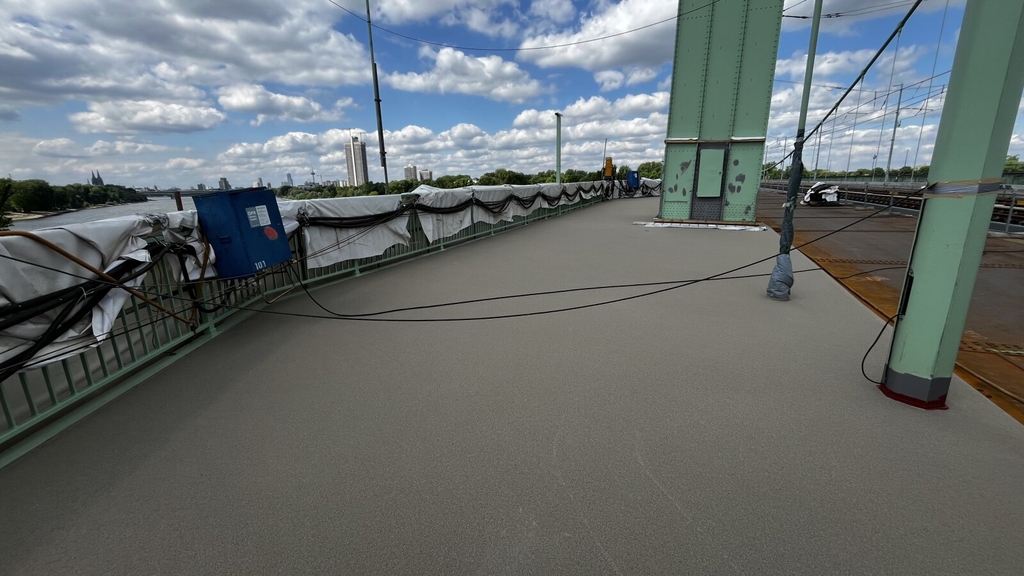 Zu sehen ist die graue Oberfläche im Bereich des Geh- und Radweges auf der Strombrücke.