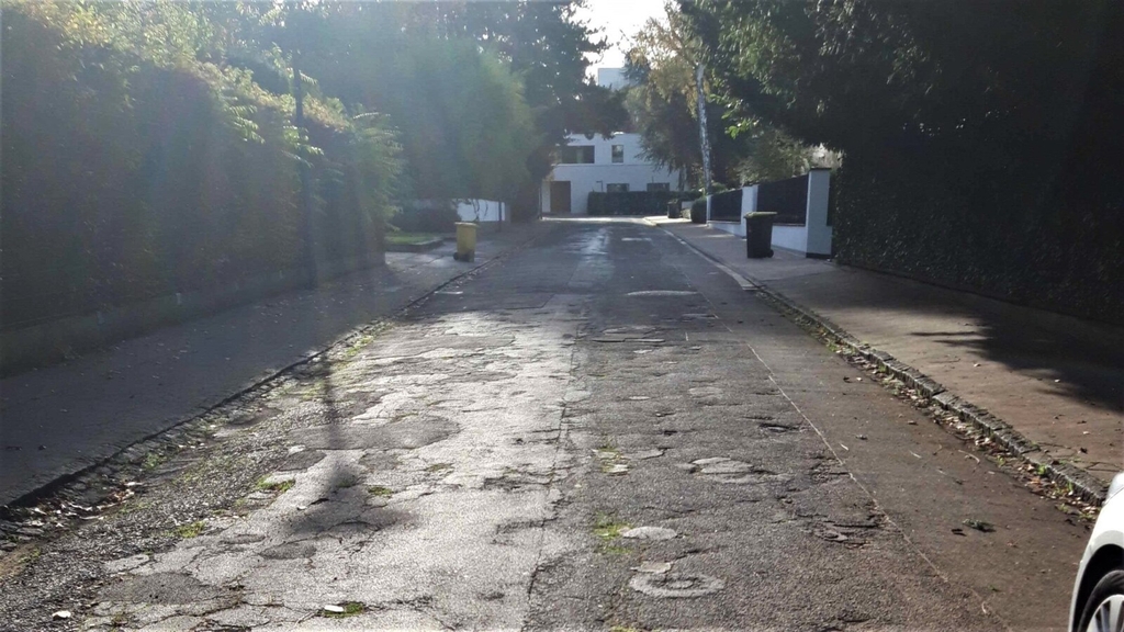 Blick auf die Straße Kärntner Weg. Die Straßendecke ist stark beschädigt.