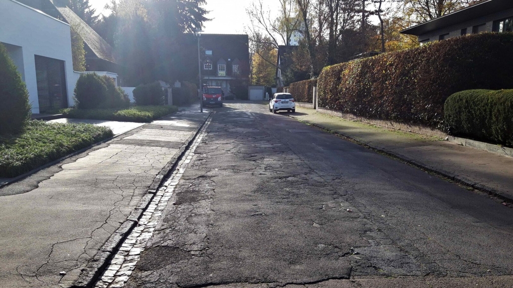 Blick in die Straße Steyrer Weg. Die Straßendecke zeigt starke Beschädigungen auf.