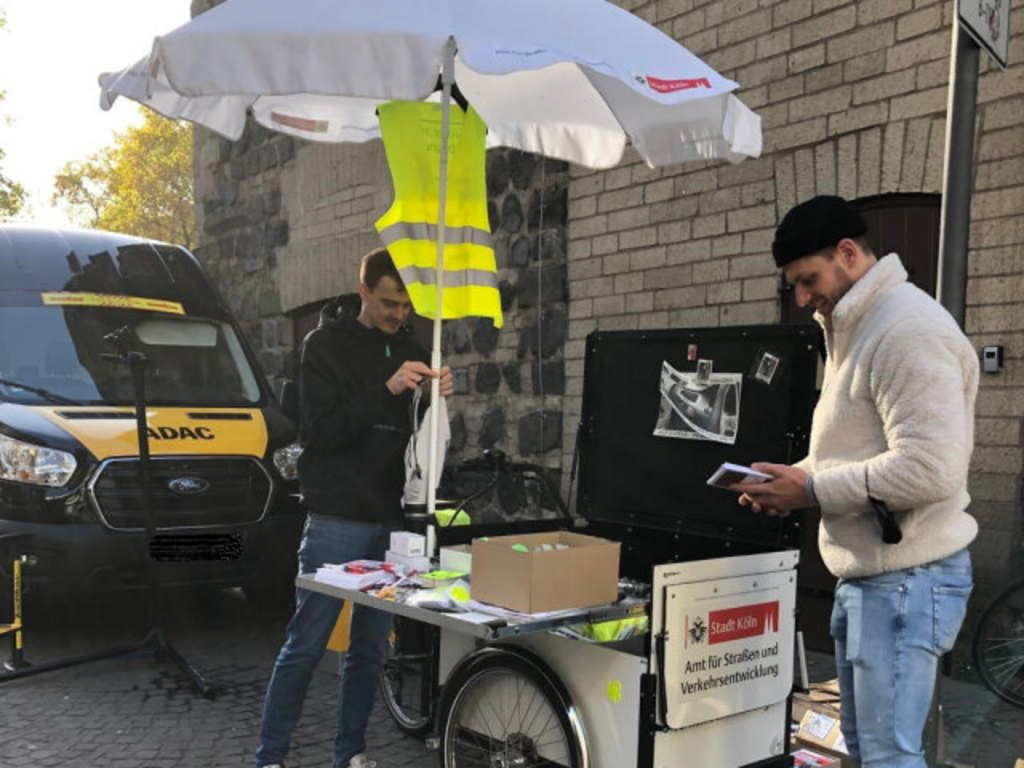 Zwei Männer vom Team des Fahrradbeauftragten stehen am Veranstaltungsfahrrad.