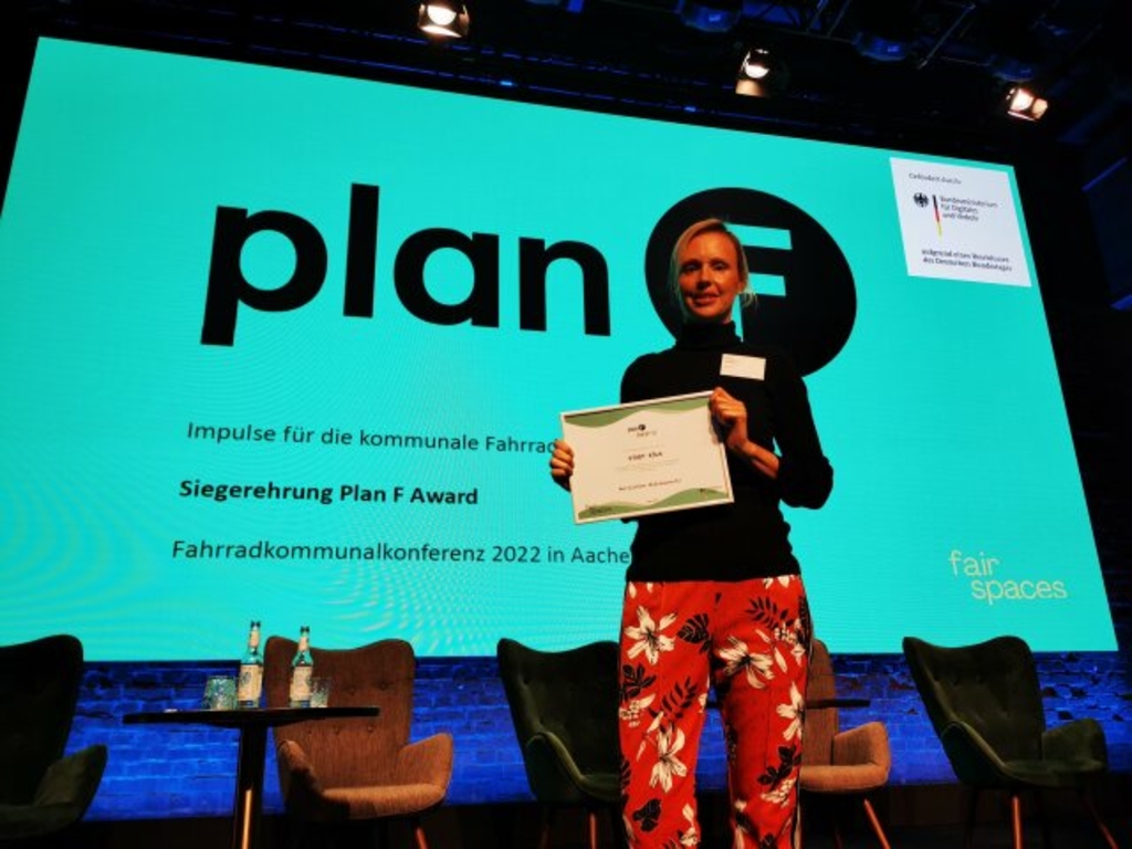 Überreichung des "Plan F"-Awards in Aachen. Projektleiterin Kristina Kollbach vom Amt für nachhaltige Mobilitätsentwicklung steht mit der Auszeichnung auf einer Bühne.
