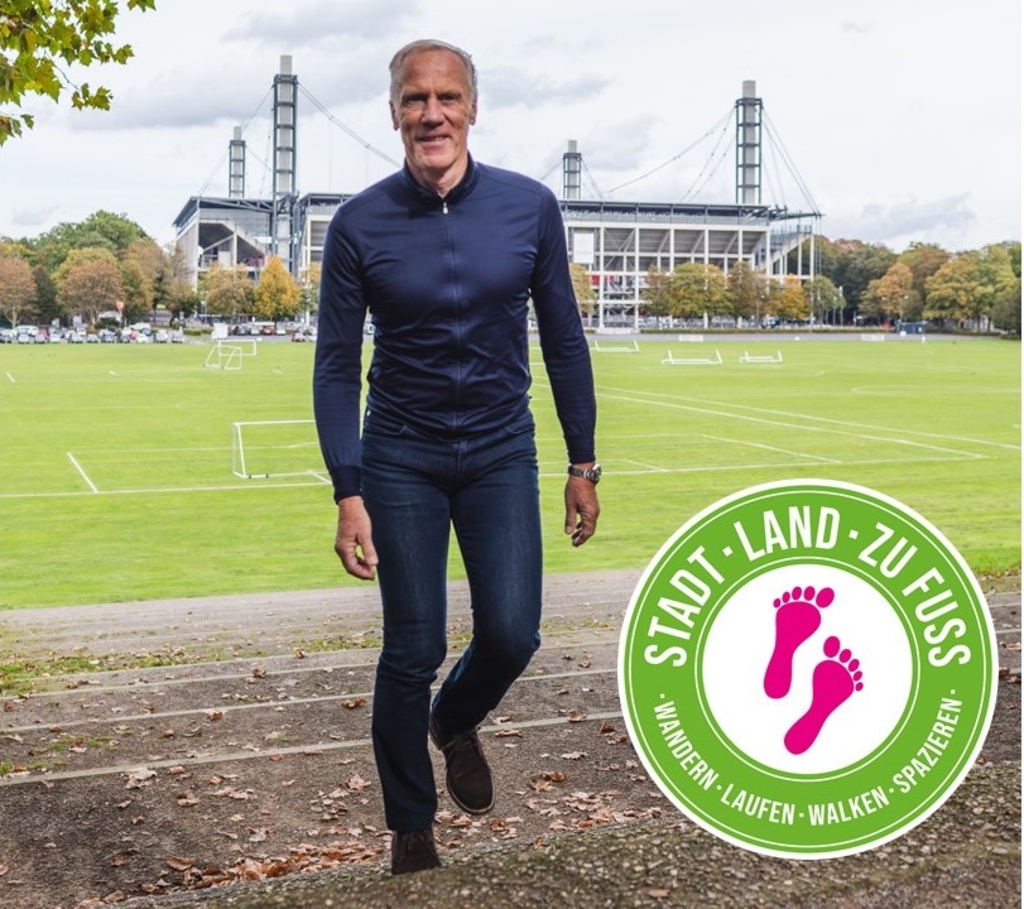 Prof. Froböse läuft Treppen hoch, im Hintergrund das RheinEnergieSTADION. Ein Textfeld informiert über die Aktion Stadt, Land, zu Fuß vom 1. bis 21. November 2024