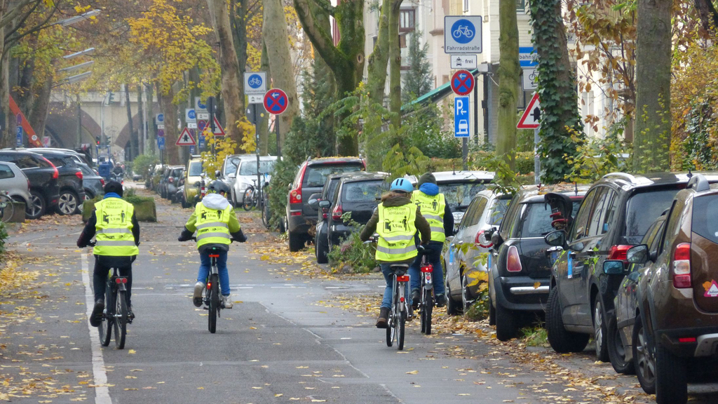 Vier Kinder auf Fahrrädern mit neonfarbenen Warnwesten auf der Fahrradstraße in der Ottostraße