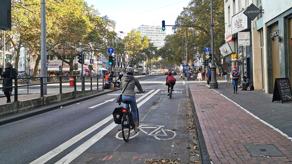 Radfahrende fahren über den neu eingerichteten Radfahrstreifen auf dem Hohenstaufenring vor der Einbiegung in den Zülpicher Platz