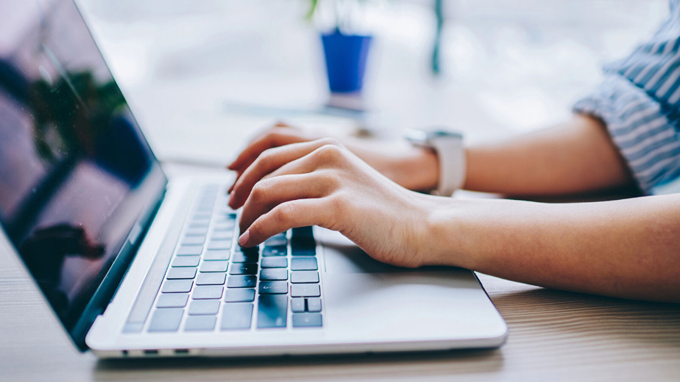Eine Frau hält ihre Hände auf eine Notebook-Tastatur