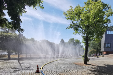 Wasserschlauch auf einem Platz aus dem Wassernebel spritzt, © Stadt Köln