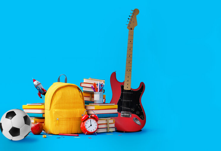 Blauer Hintergrund. Auf der linken Seite des Bildes Bücher, ein Apfel, ein gelber Rucksack, eine Gitarre, ein roter Wecker, ein Fußball und Stifte., © Gitarre: Africa Studio, Fußball: popovaphoto, Grundmotiv: Ilija Erceg
